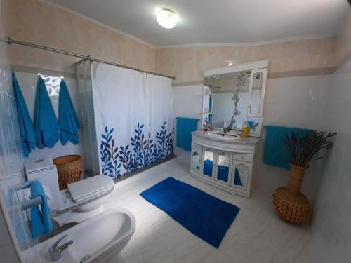 y baño azul y blanco con lavabo y ducha. en Centenária, en Oiã