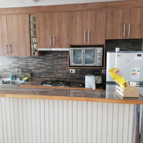 a kitchen with a stove and a microwave and a refrigerator at Departamento amoblado in Talca
