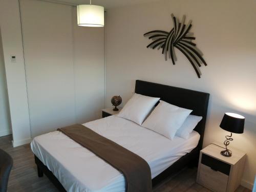 1 dormitorio con 1 cama y una planta en la pared en Béguinage le Val d'Or, en Paray-le-Monial