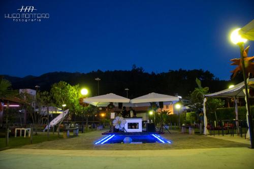 a swimming pool at night with a table and umbrellas at Alojamento das Caldas in Caldas de Aregos