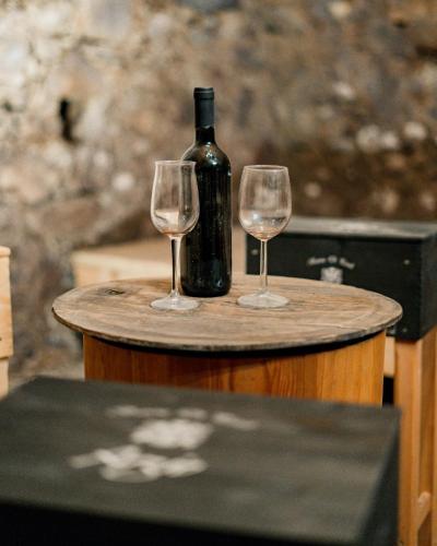 two wine glasses and a bottle on a barrel at Arzenhof, Baron Di Pauli in Caldaro
