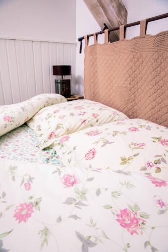 a bed with a floral bedspread and pillows on it at Hôtel Restaurant Domaine De Basil in Orbey