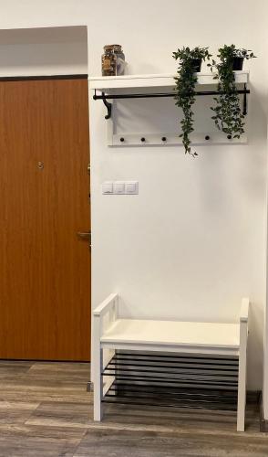 a white bench sitting next to a wall with plants at Hősök Tornya Apartman in Kőszeg