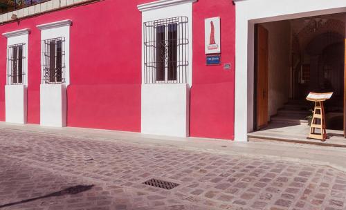 a red and white building with a chair in the doorway at Hotel Boutique Casa Catrina in Oaxaca City