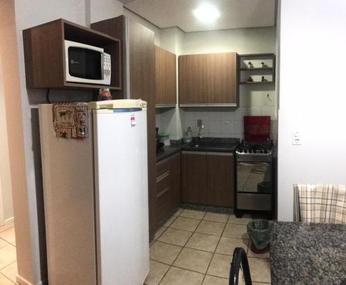 une cuisine avec un réfrigérateur et un micro-ondes dans l'établissement Apto em Torres próximo a praia, à Torres
