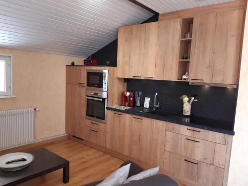 une cuisine avec des placards en bois et une table dans l'établissement Gîte Les Glycines, à Gérardmer