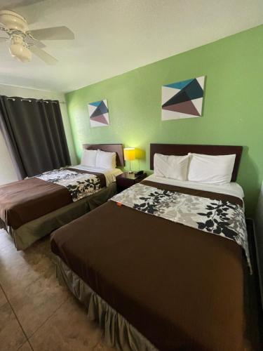 two beds in a hotel room with green walls at Hwy 59 Motel Laredo Medical Center in Laredo