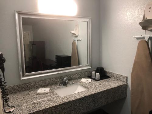a bathroom with a sink and a large mirror at Hwy 59 Motel Laredo Medical Center in Laredo