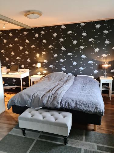 Un dormitorio con una cama con una pared negra con nubes en Östra Karup Båstad, en Östra Karup