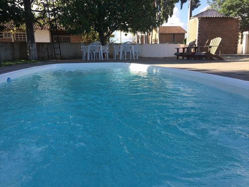 Una piscina de agua azul con sillas blancas. en Pousada Vale do Gravatá, en Gravatá
