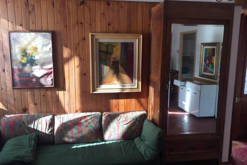 a living room with a couch and paintings on the wall at Nel set di piccolo mondo antico Villa Viola in Valsolda