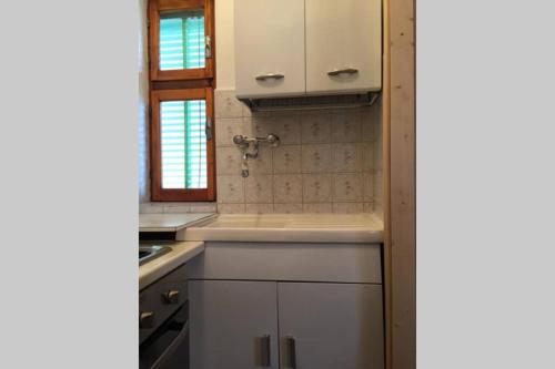 a kitchen with white cabinets and a sink at Nel set di piccolo mondo antico Villa Viola in Valsolda