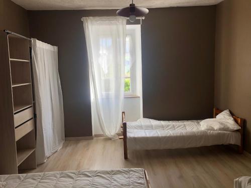 1 dormitorio con 2 camas y ventana en Maison campagne au col du festre en Le Dévoluy