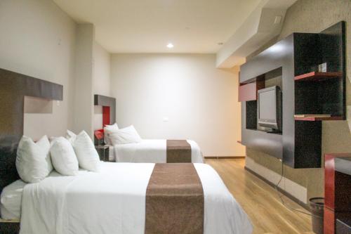 Tlaxcala de XicohténcatlにあるHotel Cancalli Business & Suitesのベッド2台、薄型テレビが備わるホテルルームです。