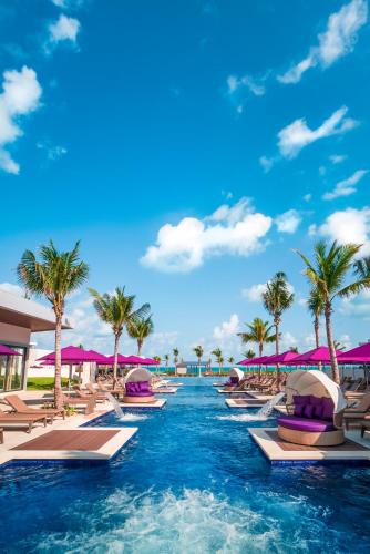 a resort swimming pool with chaise lounges and palm trees at Planet Hollywood Cancun Adult Scene by Royalton, An Autograph Collection All-Inclusive Resort - Adults Only in Cancún