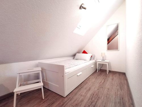 a small white bedroom with a bed and a ladder at Pension Hohaus in Neuharlingersiel