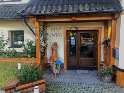 - un petit bâtiment avec une entrée et une porte en bois dans l'établissement Apartamenty Inny Świat Zakopane, à Zakopane