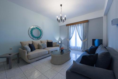 a living room with couches and a chandelier at Fedra Mare in Agios Stefanos