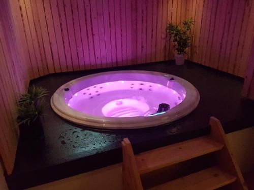 a bath tub in a room with a wooden chair at Jacuzzi & Sauna Villa 2 in Tzummarum