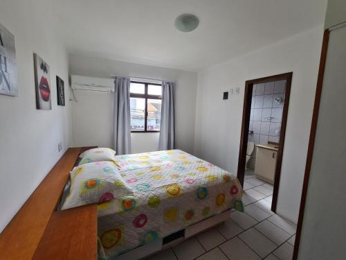 a small bedroom with a bed and a mirror at Apartamento Avenida in Bombinhas