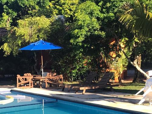 a picnic table and umbrella next to a swimming pool at Boipeba Paradise Guest House in Ilha de Boipeba