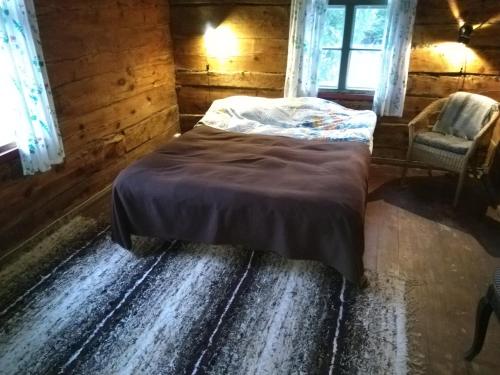 a bedroom with a bed and a chair and windows at Paali cottages in Tornimäe