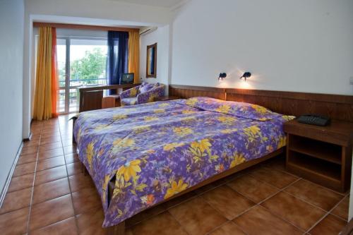 une chambre avec un lit avec une couette violette dans l'établissement Regina Hotel, à Sunny Beach