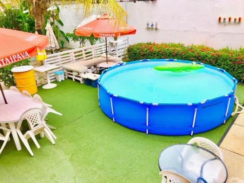 嘎林海斯港的住宿－Ótima Localização casa, 7 quartos-Porto de Galinhas 900m piscinas naturais，一个带桌椅和遮阳伞的游泳池