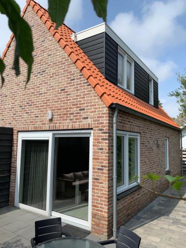 une extension vers une maison en briques avec portes coulissantes en verre dans l'établissement Beachhouse Zeewinde, à Zoutelande