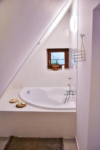 a white bathroom with a bath tub under the stairs at Eged Cottage in Eger