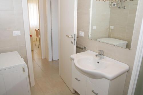 Baño blanco con lavabo y espejo en Residence Equilio Family Apartments, en Lido di Jesolo