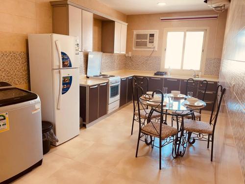 a kitchen with a table and chairs and a refrigerator at الخزامى in Al Ahsa