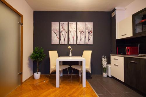 a dining room with a white table and chairs at Apartman Aurelius - private parking in Osijek