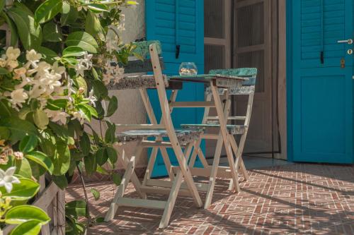 a wooden chair sitting next to a table and blue doors at La Casa del Limoneto in Favignana