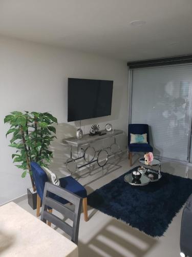 マサトランにあるDepartamento en malecon Portico Beachのリビングルーム(テレビ、テーブル、椅子付)