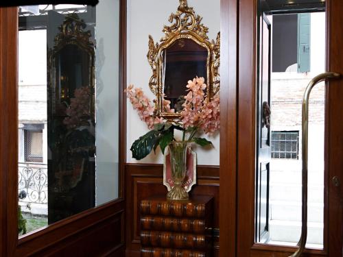 a vase with flowers on a table in front of a mirror at Hotel Ca' dei Conti in Venice