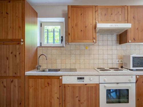 une cuisine avec des armoires en bois et un four blanc dans l'établissement Courry Hideaway with Private Pool, à Courry