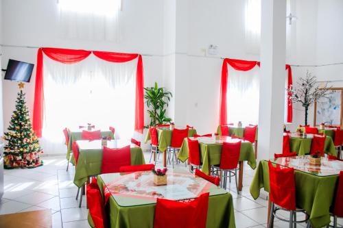 a dining room with red and green tables and a christmas tree at Hotel Palugi in Joinville