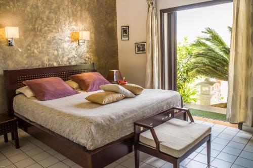 a bedroom with a bed and a large window at Hotel Hibiscus in Koné