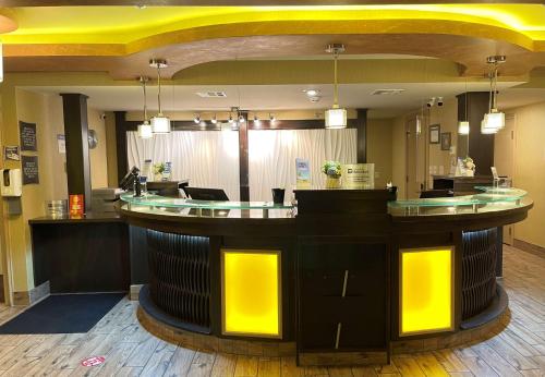 a bar in a salon with yellow lights at Best Western Aspen Hotel in Fort Smith