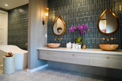 a bathroom with two sinks and two mirrors at Bann at Oak Knoll Napa in Napa