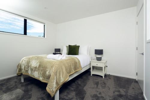 a white bedroom with a bed and a window at Armagh 221 - Christchurch Holiday Homes in Christchurch