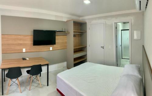 a bedroom with a bed and a desk with two chairs at Residencial Batista in Bombinhas