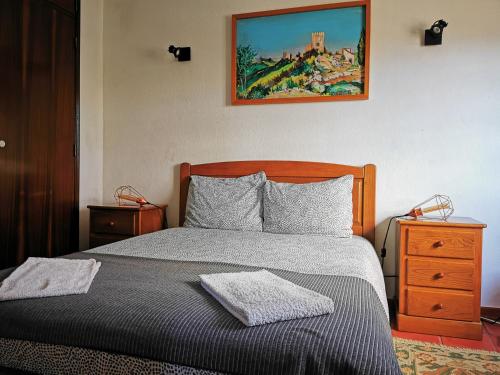 sypialnia z łóżkiem i obrazem na ścianie w obiekcie Óbidos - Casa do Castelo w mieście Óbidos