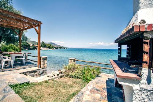 a house with a bench next to the water at Villas Nies Seaside Appartments in Soúrpi