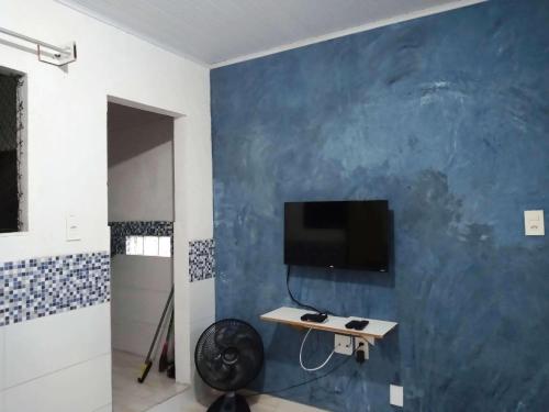 um quarto com uma televisão numa parede azul em Quarto.sala topázio em Maceió