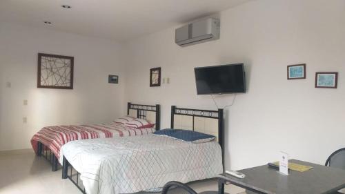 two beds in a room with a tv on the wall at Depto Las Puertas de la Ría #6 in Campeche