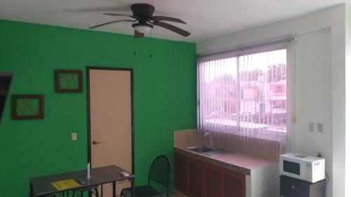 a room with a green wall and a ceiling fan at Depto Las Puertas de la Ría #6 in Campeche