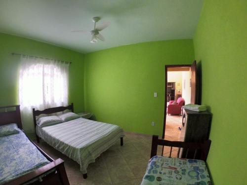 een slaapkamer met groene muren en 2 bedden en een spiegel bij Casa da Mamãe in Barra de São João
