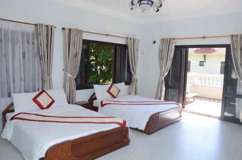 a bedroom with two beds and a large window at DTC Hotel in Da Nang